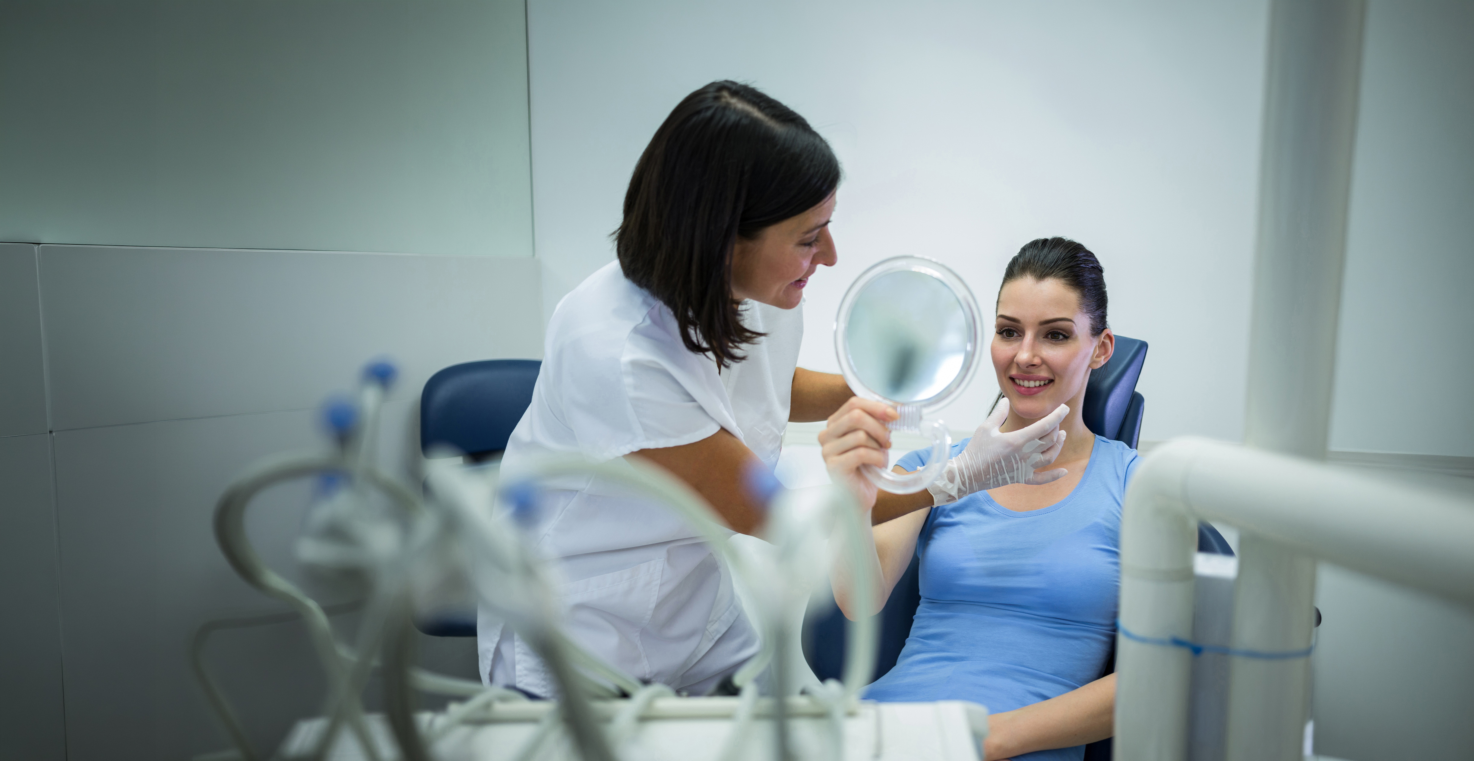 Dentist showing a patient her smile in a hand mirror.