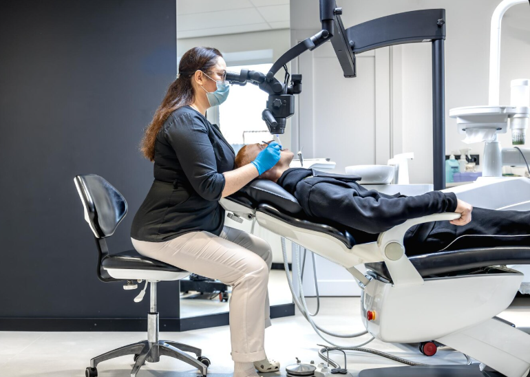 Dentist providing care to a patient in a treatment room.